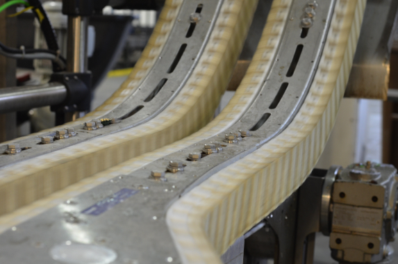 A close-up view of the Rexroth VarioFlow conveyor line that cradles glass beer bottles within the center opening of the wedge conveyor safely transporting product up a 45-degree incline.