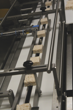 A row of freshly-made marshmallow crispy squares is fed towards the flowrapping section via a fast-moving split conveyor belt that can be easily changed by plant’s personnel to accommodate fast product changeovers in minutes without any tools.