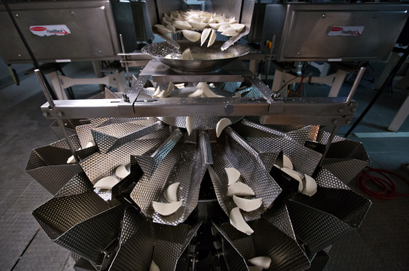 The Ishida RS-214W-S/30-PB multihead scale manufactured by Heat and Control carefully weighs out pre-determined portions of perogies before dispensing them below into the model XM15PR vertical form, fill and seal flexible film bagger (picture above) manufactured by the Chicago-based Triangle Package Machinery Co.