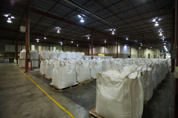 Massive batches of freshly blended and screened dishwasher powder detergent are  placed into heavy-duty woven bulk super-sacks in sequential order prior to packaging.