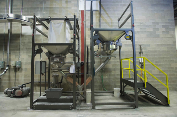 A heavy-duty bulk discharger and bucket elevators from UniTrak Corporation are used to transfer bulk powder up to the automatic weighscales on the mezzanine level above.