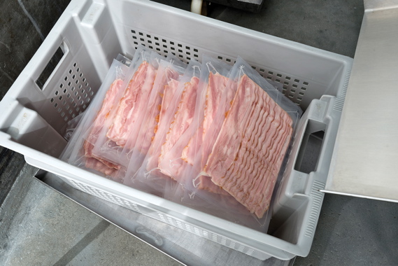 Packs of veal bacon await application of exterior brand packaging after being hermetically sealed in clear film packaging supplied by Norstar.
