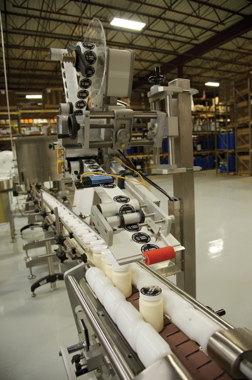After filling and capping, a Capmatic LabelStar System 3 labeler is used to apply a top-dot adhesive label onto bottle caps for additional branding impact.