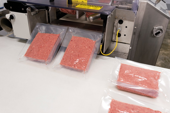 Processed and packed for industrial sale, packs of ground meats exit a VC999 RS420c thermoformer that has helped BestCo Foods achieve notable reductions in packaging time and costs.