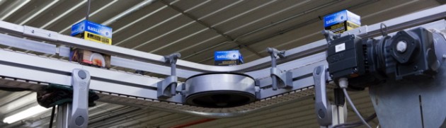 An SEW-Eurodrive motor helps provide a smooth turn for cartons of cigarettes on the elevated FlexLink conveyor line.