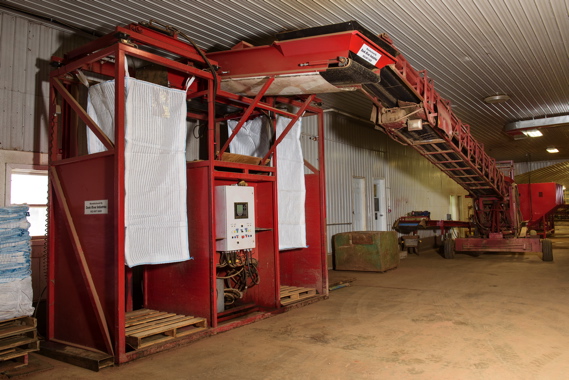Monaghan Farms uses an automatic tote filler from Dunk River Industries to fill 3,400 pound bags in under two minutes, with an elevator lifting empty bags up to the top, and lowering them slowly as it fills to prevent product damage.