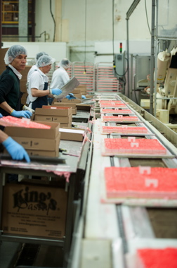 Line workers at the King’s Pastry plant in Mississauga placing trays of freshly decorated pre-cut pieces of moist and delicious raspberry layered mousse cake inside the Norampac corrugated boxes used for bulk product shipments to foodservice customers.