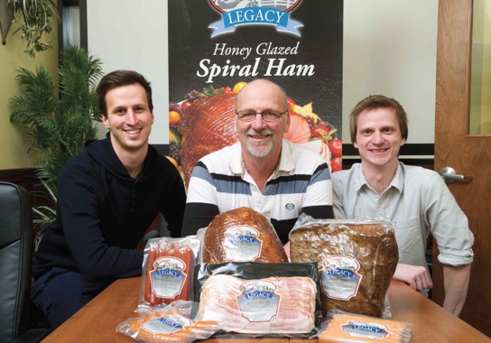 Maintaining the family tradition are (from left) Schinkel’s Legacy production manager Kevin Schinkel, owner and president Tim Schinkel, and office manager Matt Schinkel, posing with some of the high-quality meat products they produce and retail at their third-generation family business in Chatham, Ont.
