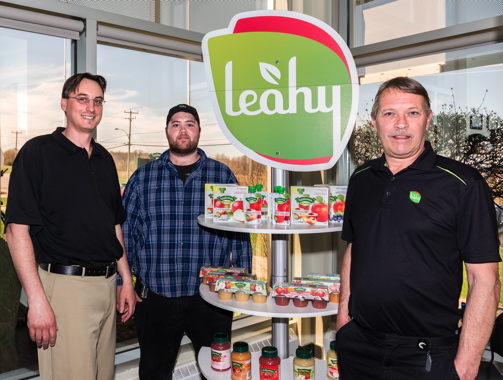  (From Left) Leahy Orchards Inc. vice-president of purchasing and logistics Philip Seguin, director of operations and supply Mitchell Leahy, and president and chief executive officer Mike Leahy with a display of Leahy brand Applesnax applesauce in a variety of packaging formats.