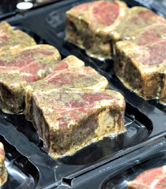A close-up of finished packages of premium-quality lamb chops vacuum-sealed on a Multivac R175 CD thermoformer using high-strength vacuum-skin packaging film from Sealed Air Corp.